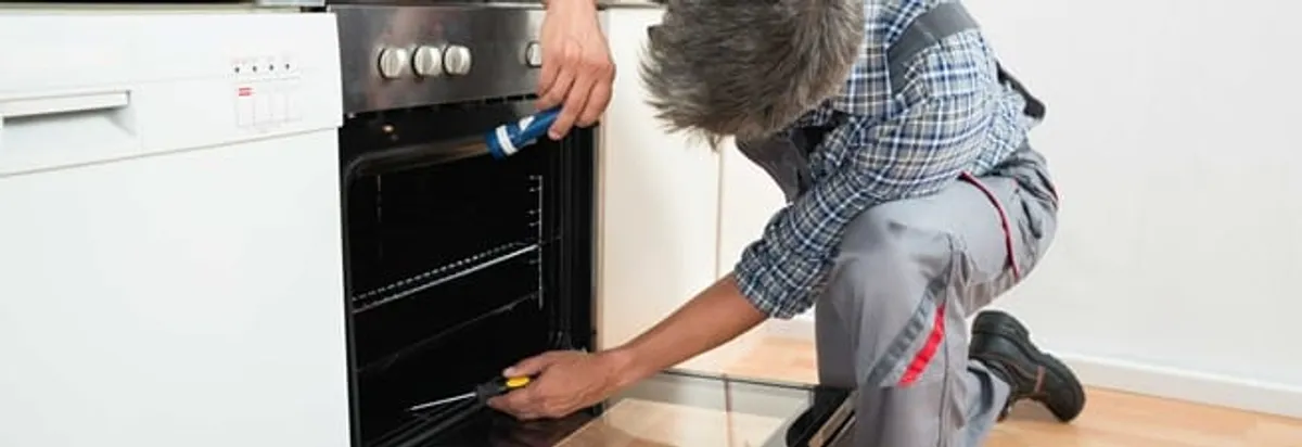 Oven repair technician inspecting and servicing an electric oven in Aurora, CO