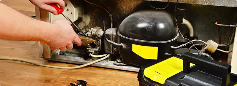 Refrigerator repair technician fixing the compressor and wiring in Aurora, CO